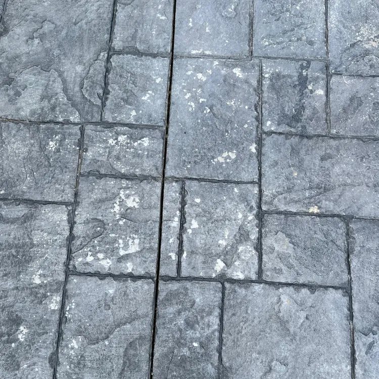 Close up of pattern imprinted concrete before sealing, grey with white blooming