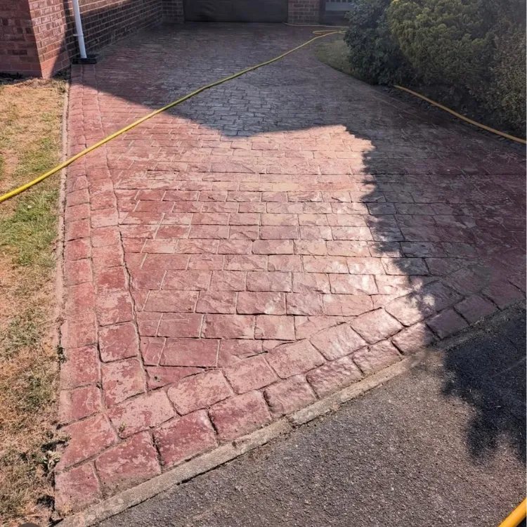 Red imprinted concrete before recolouring, worn and patchy