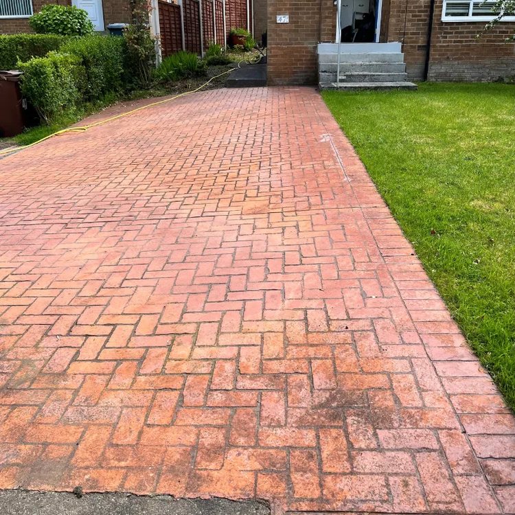 Red imprinted concrete driveway before pressure washing