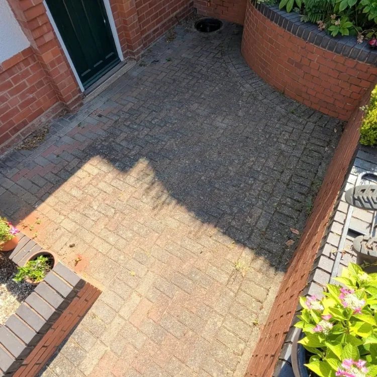 Block paved area by a front door before cleaning, dark and stained