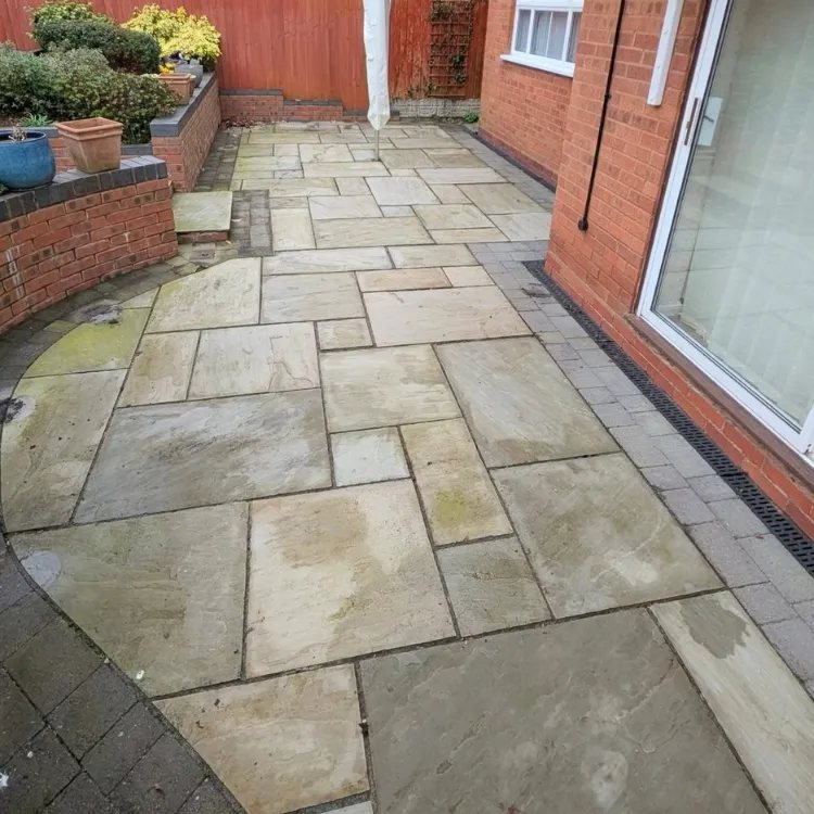 Sandstone patio beside patio doors before jet washing, green with algae