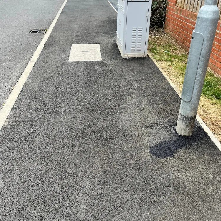 Tarmac footpath on a housing estate before restoration, faded grey