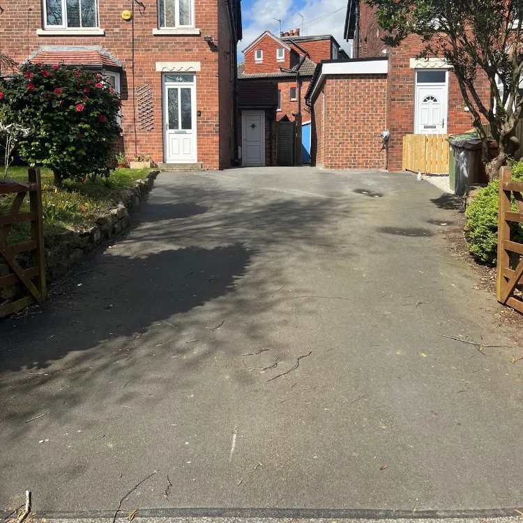 Tarmac driveway in front of brick houses before restoration, faded and patchy