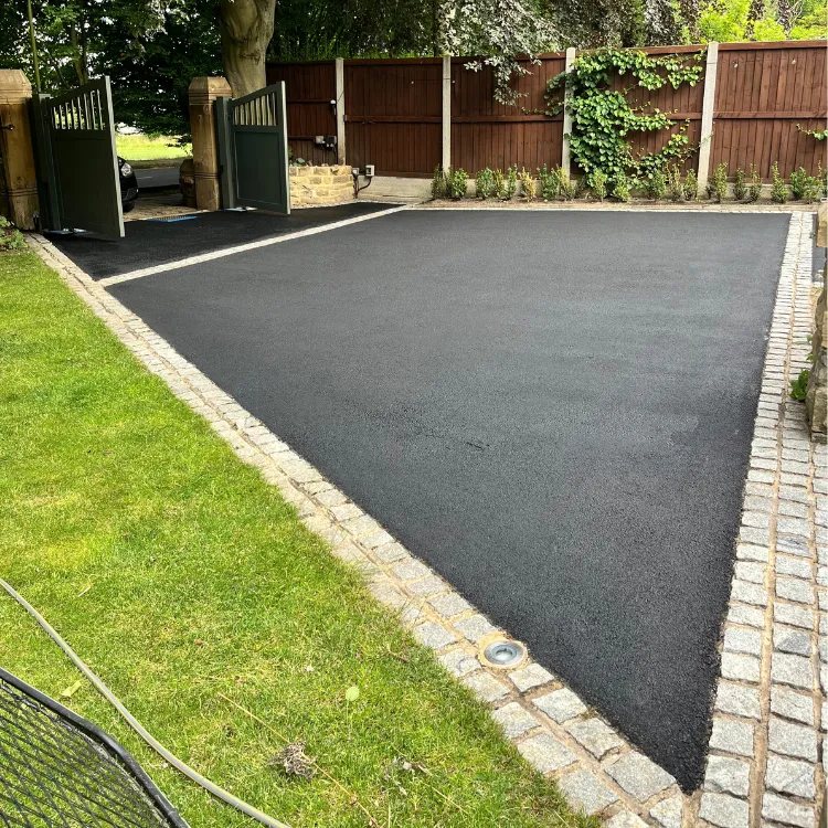 The same parking area after restoration, black with a granite sett edge