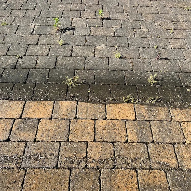 Close up of block paving, cleaned in the foreground and still black with grime and weeds behind