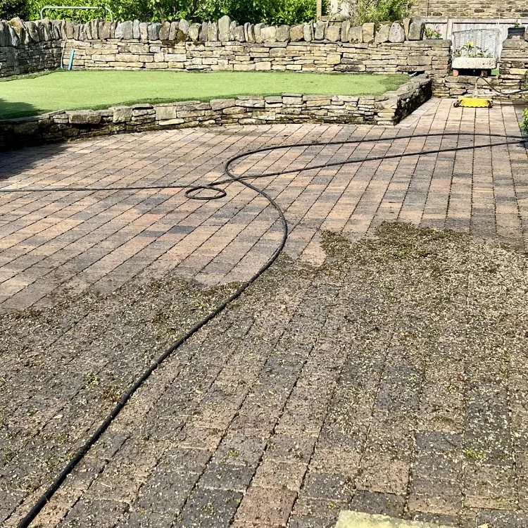 Block paved area half cleaned, the hose lying across the half still to do