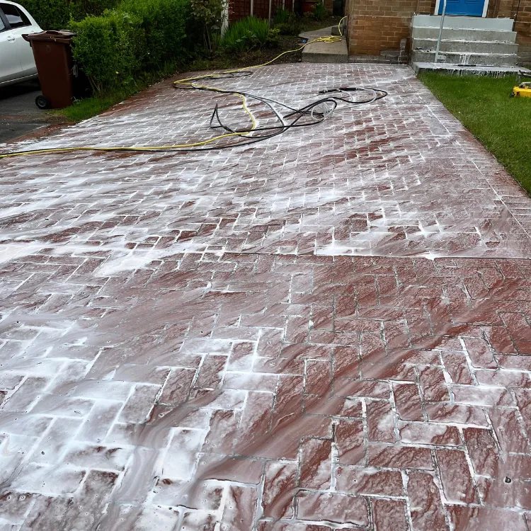 Cleaning treatment foaming on a red imprinted concrete driveway