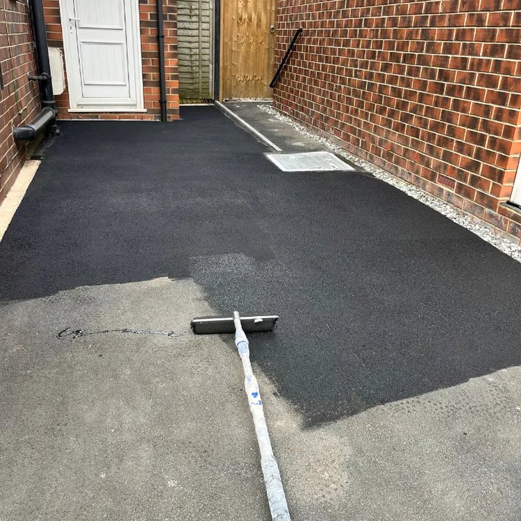 Tarmac restorer being brushed across a driveway